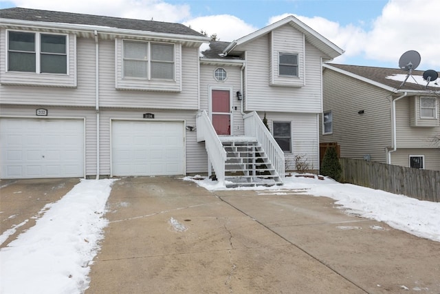 split foyer home with concrete driveway, fence, and an attached garage