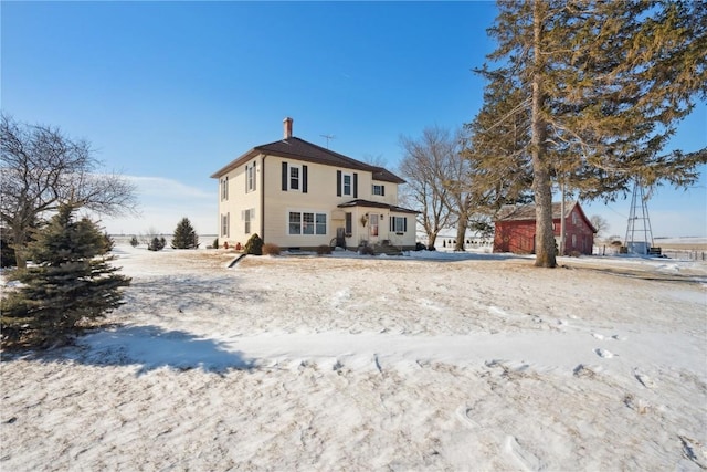 snow covered back of property featuring a garage and a chimney