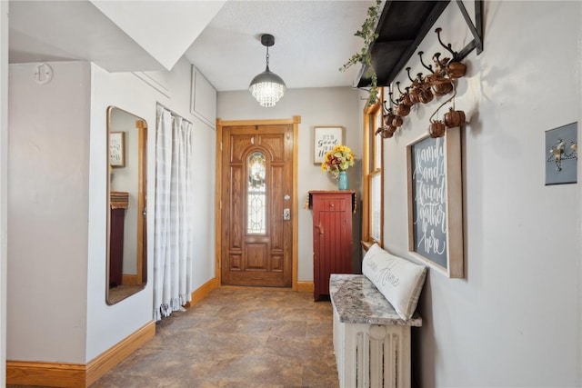 entrance foyer with a chandelier and baseboards