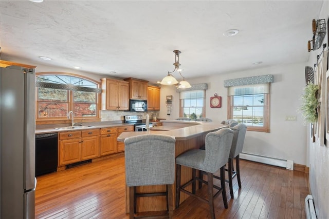 kitchen featuring black appliances, a baseboard heating unit, light countertops, and a sink