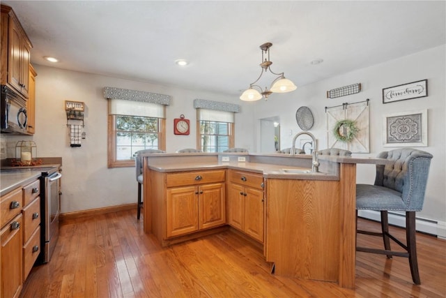 kitchen featuring a kitchen island with sink, a sink, stainless steel range with electric stovetop, black microwave, and a kitchen breakfast bar