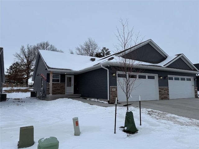 single story home featuring an attached garage, stone siding, and central AC