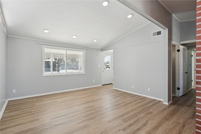 unfurnished living room with ornamental molding, lofted ceiling, light wood-type flooring, and visible vents