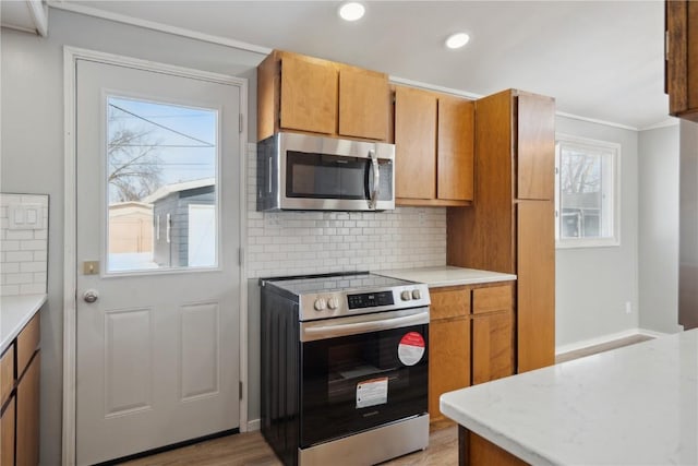 kitchen featuring stainless steel appliances, brown cabinets, light countertops, and backsplash