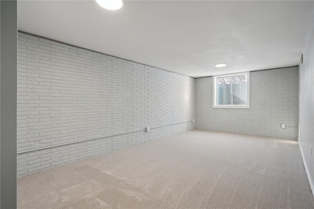 unfurnished room with brick wall and light colored carpet