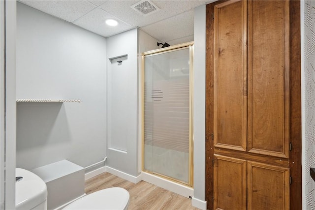 full bathroom featuring a paneled ceiling, visible vents, a shower stall, wood finished floors, and baseboards