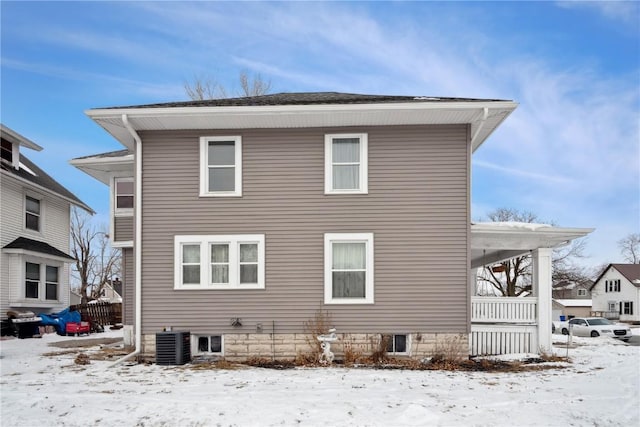 snow covered rear of property featuring cooling unit