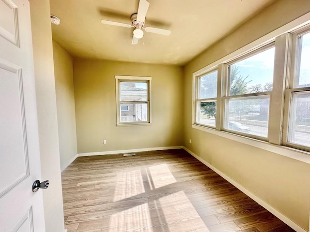 empty room featuring light wood finished floors, baseboards, and a ceiling fan