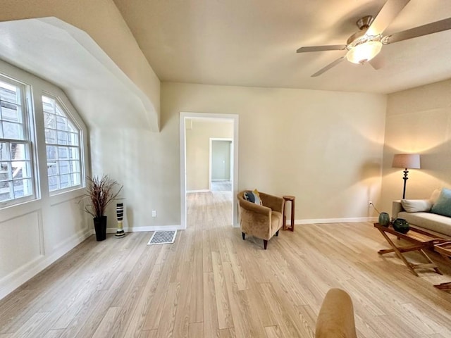 living area with ceiling fan, light wood-type flooring, visible vents, and baseboards