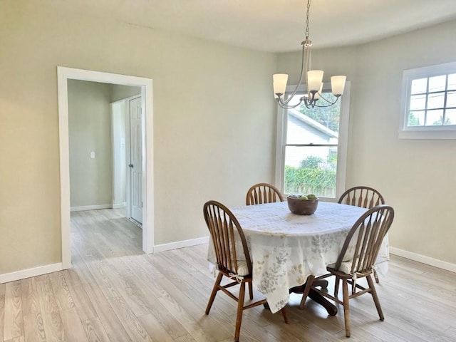 dining space with light wood finished floors, baseboards, and an inviting chandelier