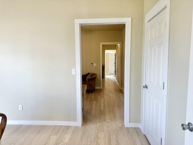 hallway featuring light wood-style flooring and baseboards