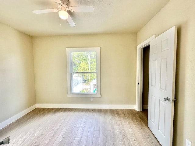 empty room with a ceiling fan, light wood-style flooring, and baseboards