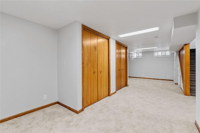 below grade area featuring baseboards and light colored carpet