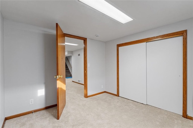 unfurnished bedroom with a closet, light colored carpet, and baseboards