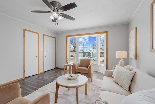 living area featuring baseboards, ceiling fan, dark wood finished floors, and crown molding