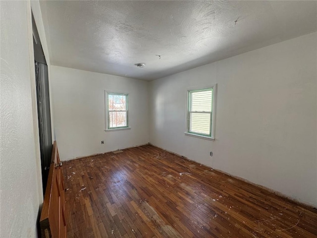 empty room featuring a textured ceiling and dark wood-type flooring