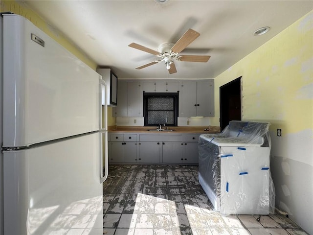 kitchen with gray cabinets, light countertops, a ceiling fan, freestanding refrigerator, and a sink