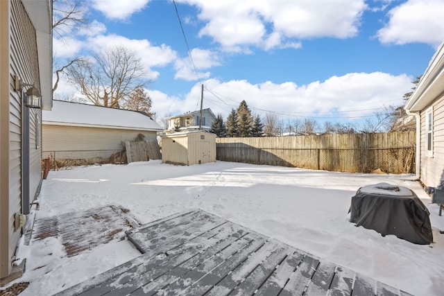 snowy yard featuring a storage shed, an outbuilding, and a fenced backyard