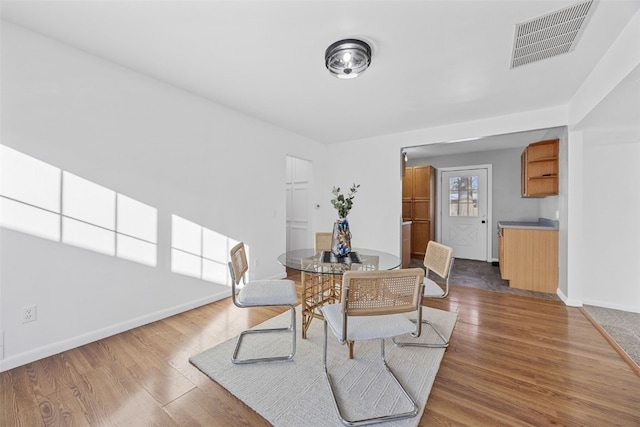 dining area featuring wood finished floors, visible vents, and baseboards