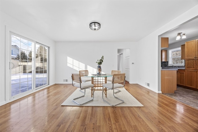 dining area featuring baseboards, visible vents, and light wood finished floors