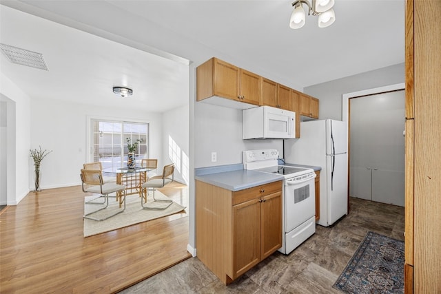 kitchen featuring light countertops, visible vents, light wood-style floors, white appliances, and baseboards