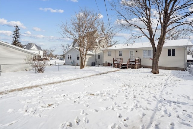 snow covered house featuring a garage, central air condition unit, and a deck