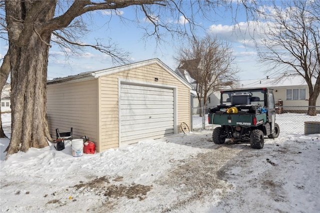 snow covered garage with a garage and fence