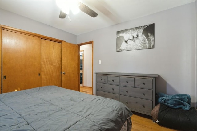 bedroom featuring light wood-style floors, ceiling fan, and a closet