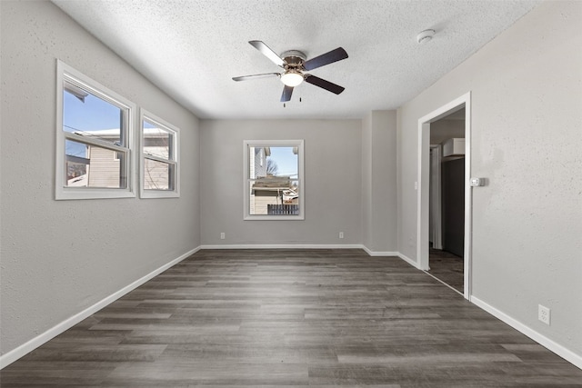 unfurnished room featuring a textured ceiling, dark wood finished floors, and baseboards