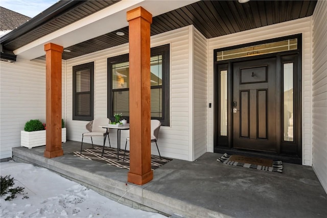 snow covered property entrance with covered porch