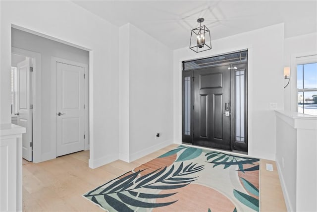 entryway featuring a notable chandelier, light wood-style flooring, and baseboards