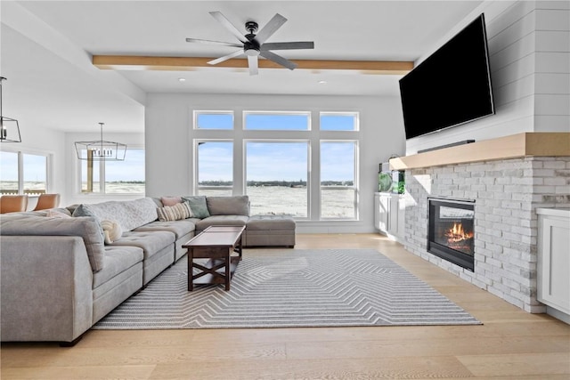 living room featuring light wood-style floors, a fireplace, a wealth of natural light, and beam ceiling