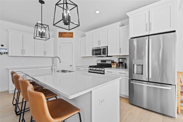 kitchen featuring appliances with stainless steel finishes, white cabinetry, and an island with sink