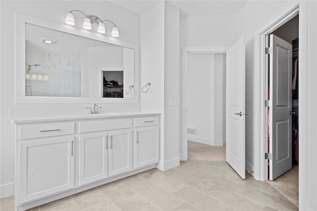 full bathroom with a walk in closet, vanity, and baseboards