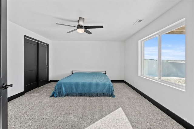 bedroom with a closet, visible vents, light carpet, ceiling fan, and baseboards