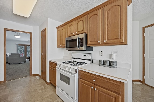 3440 Sunburst Ave, Marion, IA 52302 - kitchen featuring baseboards, white range with gas stovetop, light countertops, a textured ceiling, and stainless steel microwave