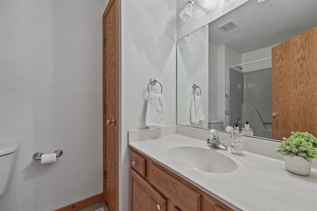 bathroom with a shower, visible vents, toilet, a textured ceiling, and vanity