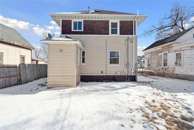 snow covered rear of property with fence