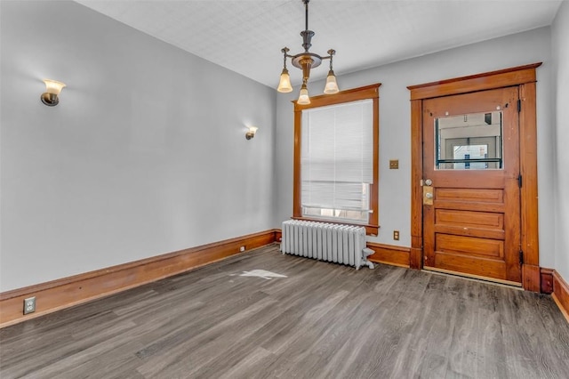 unfurnished dining area with radiator, a healthy amount of sunlight, baseboards, and wood finished floors