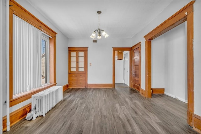 interior space featuring radiator, baseboards, a chandelier, and wood finished floors