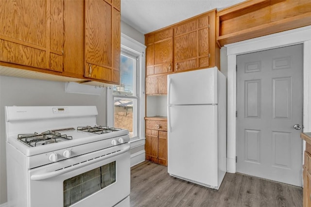 kitchen featuring white appliances, brown cabinetry, and light wood-style floors