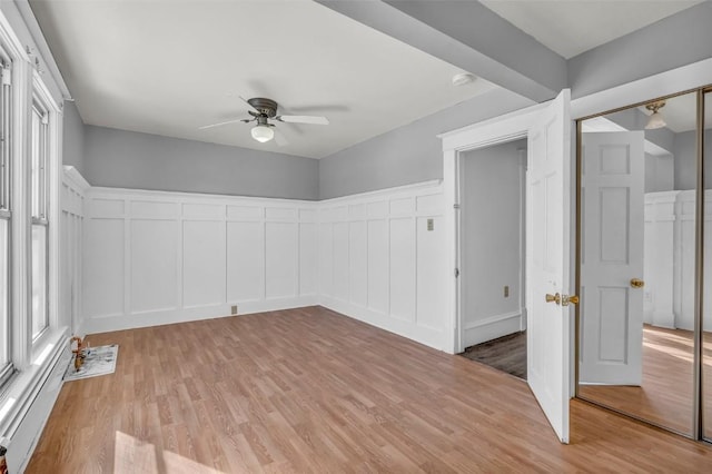 unfurnished room with ceiling fan, a wealth of natural light, a baseboard radiator, and light wood-style flooring