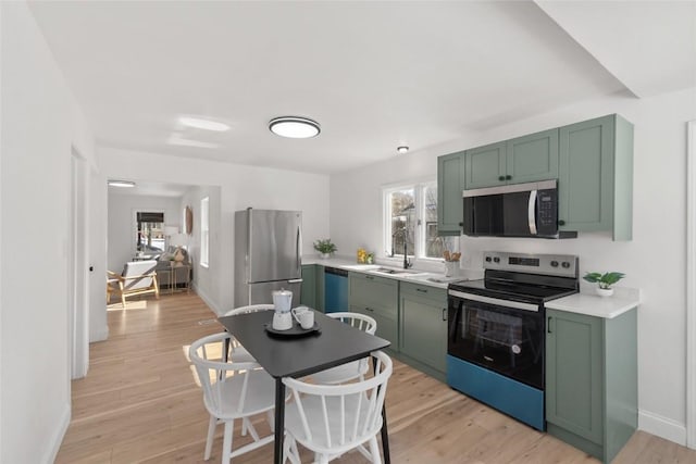 1421 Broadway St, Iowa City, IA 52240 - kitchen featuring green cabinets, appliances with stainless steel finishes, a sink, light countertops, and light wood-type flooring