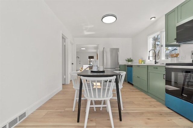 kitchen featuring visible vents, light wood-style floors, green cabinets, light countertops, and appliances with stainless steel finishes