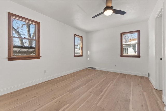 spare room featuring light wood-style flooring, visible vents, ceiling fan, and baseboards