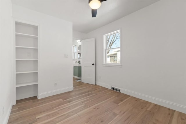 unfurnished bedroom with a ceiling fan, light wood-type flooring, visible vents, and baseboards