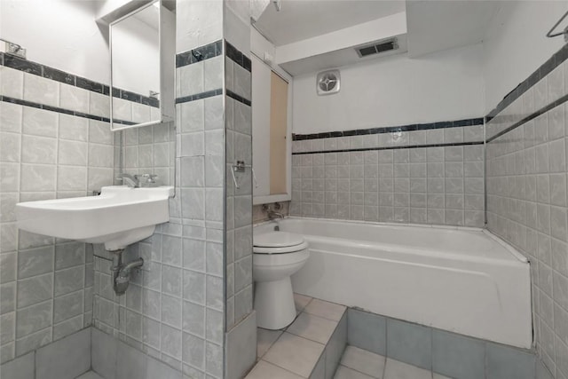 bathroom featuring visible vents, toilet, a bath, tile patterned flooring, and tile walls