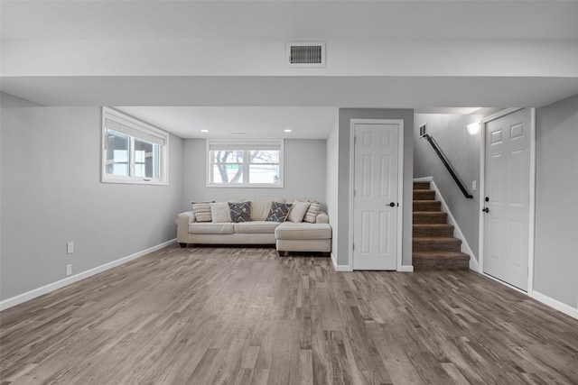 unfurnished living room with stairway, wood finished floors, visible vents, and baseboards