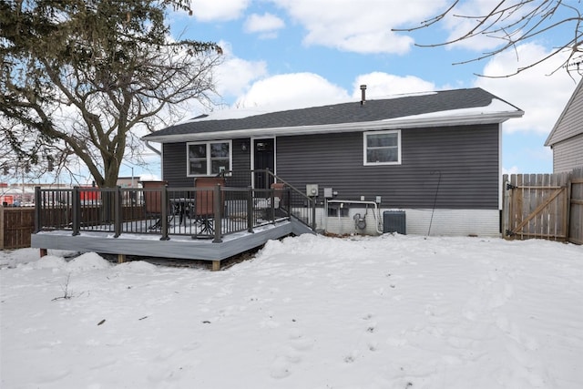 snow covered back of property featuring fence, a deck, and central air condition unit