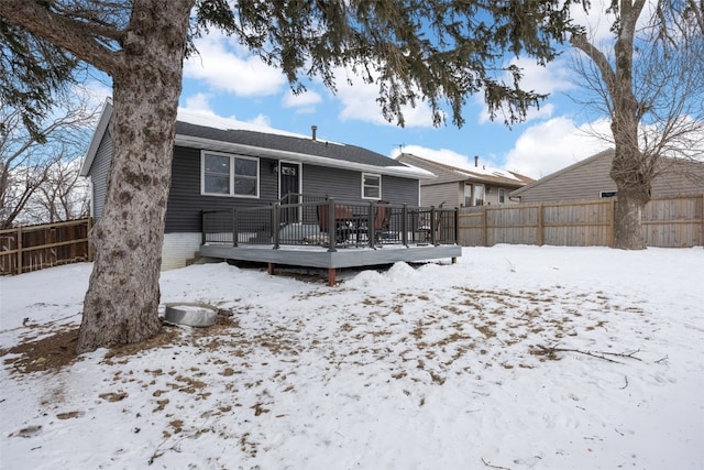 snow covered house featuring a fenced backyard and a deck